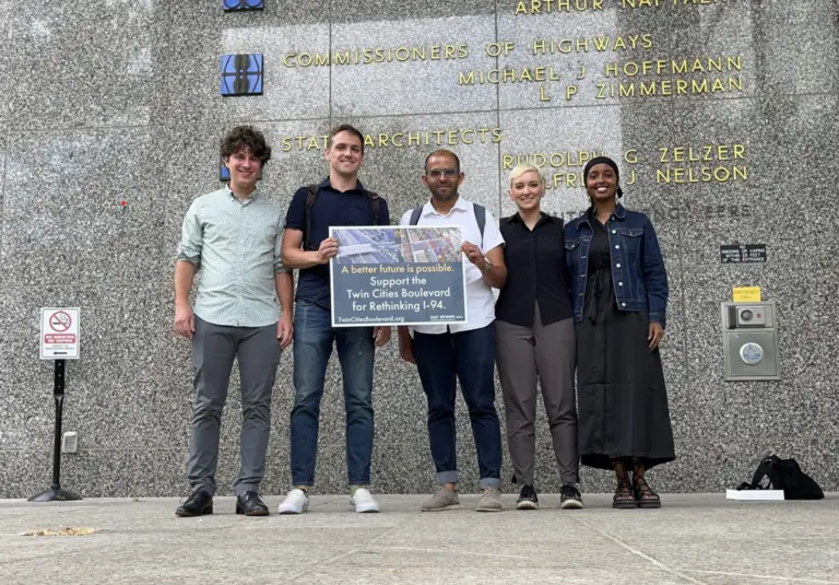 open streets team holding up sign supporting the rethinking of I-94